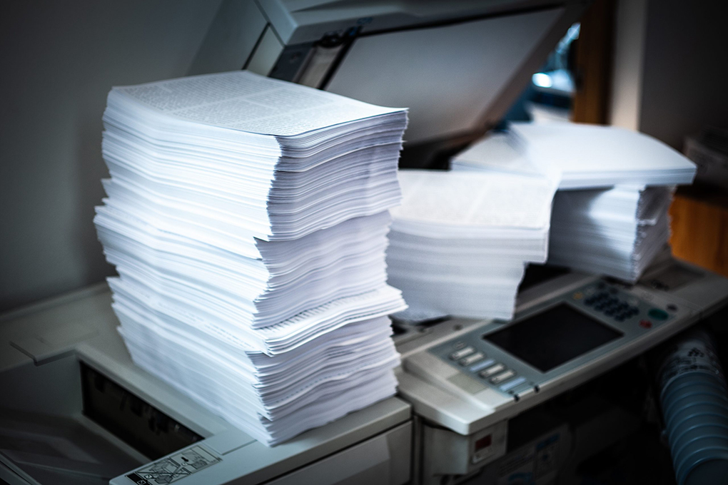 An image of a pile of papers above a printer