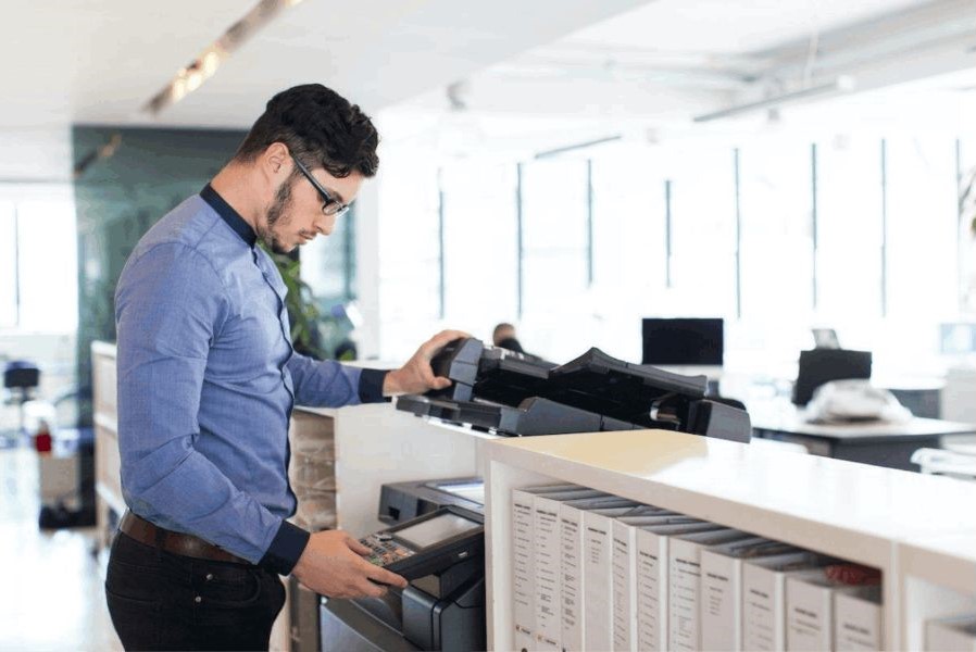 Un hombre frente a una impresora, escaneando un documento