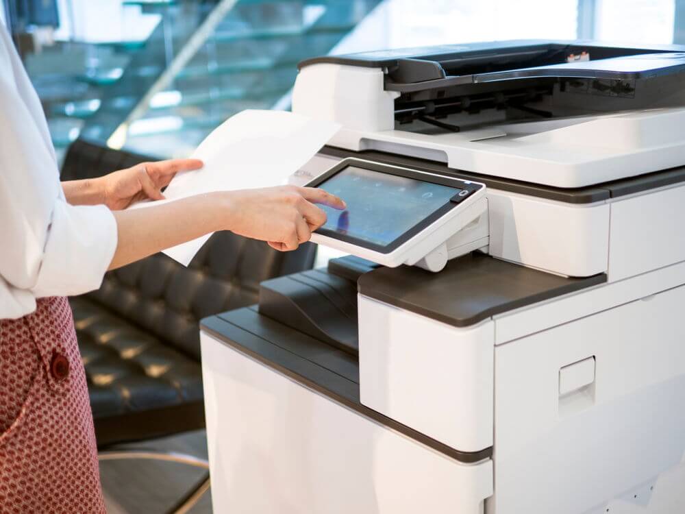 Una persona con un papel en frente a una impresora